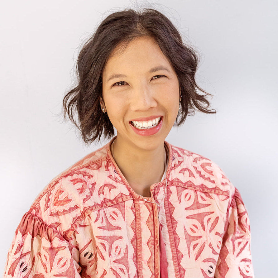 Woman wearing a pink patterned blouse against a white background