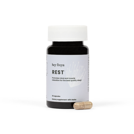 REST – Premium REM and Sleep Regulation Supplement for Women, Melatonin-Free. Housed in an upright amber bottle with a pale blue label. A daily dose of hey freya’s sleep support capsule rests against the bottle. Serenely positioned against a white background, offering a natural sleep solution.