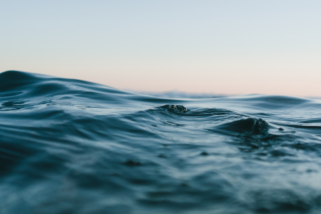 A detailed close-up of the ocean's surface, its deep grey-blue hues evoking a sense of refreshing hydration.