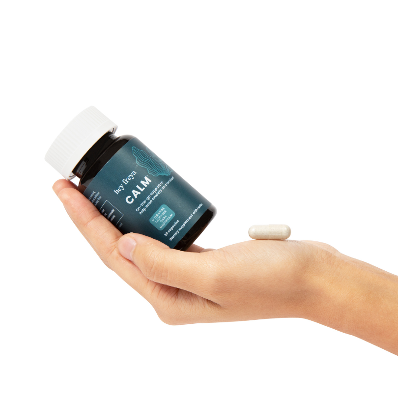 hey freya's CALM supplement which is on-the-go help to ease anxiety and tension. The petite bottle of CALM rests in a woman's hand with a single dose of CALM, one capsule, resting on her palm