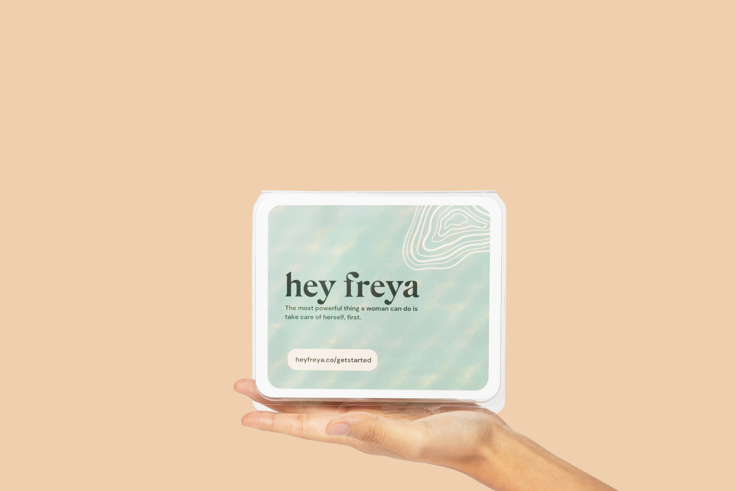 Hand holding a 'hey freya’ stress test kit against a beige background